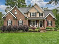 Charming brick home featuring manicured lawn and cozy front porch with rocking chairs at 3409 Valdosta Ct, Monroe, NC 28110