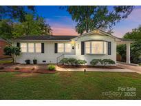 Charming single-story home featuring a white brick facade, manicured landscaping, and a covered carport at 4106 Castlewood Rd, Charlotte, NC 28209