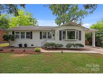 Charming single-story home featuring a brick facade, black shutters, mature landscaping, and a well-manicured lawn at 4106 Castlewood Rd, Charlotte, NC 28209