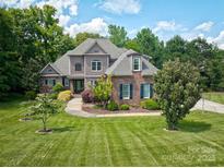 Beautiful brick home with a landscaped yard, mature trees and a curved walkway leading to the front door at 5826 Natoma Rd, Lake Wylie, SC 29710