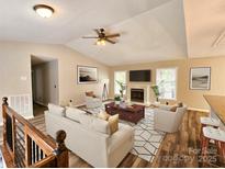 Bright living room with fireplace, ceiling fan, and wood floors showcases a comfortable and inviting space at 7154 Woodcock Trl, Stanley, NC 28164