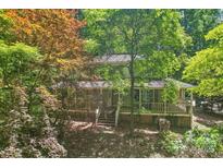 Two-story home with a covered front porch surrounded by lush greenery and mature trees at 8504 Knollwood Cir, Charlotte, NC 28213