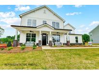 Inviting two-story home with a charming front porch, stone accents, and manicured lawn at 8692 Acadia Pkwy # 591, Sherrills Ford, NC 28673