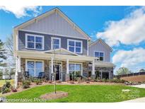 Charming two-story home with a landscaped yard, stone accents, and inviting front porch with rocking chairs at 8692 Acadia Pkwy # 591, Sherrills Ford, NC 28673