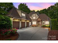 Charming Tudor-style home boasts three-car garage, beautiful stone accents, and a manicured front yard at 104 Golden Bell Ct, Mooresville, NC 28117