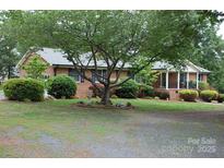 Charming brick home featuring a mature tree and well-manicured landscaping at 116 Lanes End Rd, Locust, NC 28097