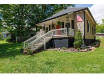 Charming home with a cozy front porch, white railing, a bright red door, and landscaped front yard at 118 Sunset Dr, Clover, SC 29710