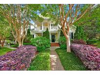 Charming two-story home featuring a welcoming porch, brick pathway, and lush landscaping, offering curb appeal at 14505 Sunset Walk Ln, Huntersville, NC 28078