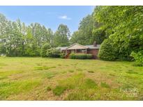 Charming brick home with a covered porch and mature trees in a spacious green front yard at 151 Deja Ln, Cleveland, NC 27013