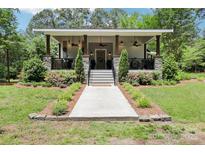 Charming single-story home featuring a welcoming front porch with stone accents and well-manicured landscaping at 1737 Hwy 109 N Hwy, Troy, NC 27371