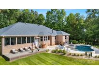 Beautiful backyard of brick home featuring a pool, patio, and well-manicured lawn at 408 Emerald Bay Dr, Salisbury, NC 28146