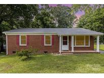Charming brick ranch home with red shutters, green lawn, and mature trees at 4915 Galax Dr, Charlotte, NC 28213