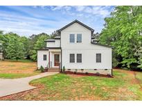 Charming new construction farmhouse with board and batten siding, lush landscaping, and inviting entry at 1011 Sandy Ct, Gastonia, NC 28056
