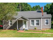 Charming single-story home featuring gray siding, a brick chimney, well-maintained landscaping, and a welcoming front entrance at 1103 Oklahoma St, Kannapolis, NC 28083