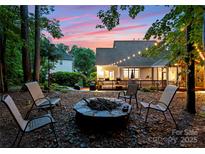 Inviting backyard with a stone firepit and string lights, perfect for outdoor entertaining at 15301 Marsh Field Ct, Huntersville, NC 28078