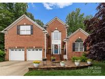 Charming brick home featuring a two-car garage, manicured lawn, and a welcoming entrance with a blue door at 15301 Marsh Field Ct, Huntersville, NC 28078