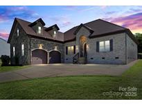 Stunning stone and brick home featuring a two-car garage, arched entrance, and well-manicured lawn at 1974 Glen Manor Ct, Lincolnton, NC 28092