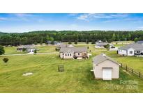 Expansive backyard with outbuilding, complemented by lush greenery and neighboring houses under a bright, clear sky at 3645 Kimber Ln, Sherrills Ford, NC 28673