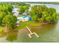 Expansive lakefront property with private dock and lush greenery surrounding a modern white house with blue accents at 3911 Sandy Point Dr, York, SC 29745