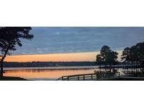 Scenic lake view featuring a serene waterfront, wooden dock, and a colorful sunset, perfect for lakeside living at 3911 Sandy Point Dr, York, SC 29745