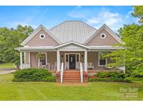 Charming home featuring a brick stairway, covered porch, and swing for relaxing, complemented by lush landscaping at 4569 Edgeland Rd, Edgemoor, SC 29712