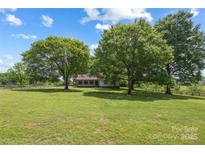 Expansive front yard with mature trees, wooden fence, and charming single-story home at 5200 Winding Ln, Indian Trail, NC 28079