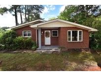 Charming brick ranch-style home with mature trees and landscaping creating an inviting curb appeal at 709 Sunset Dr, Salisbury, NC 28147