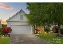 Charming home with a two-car garage, manicured lawn, and lovely landscaping at dusk at 8410 Darcy Hopkins Dr, Charlotte, NC 28277