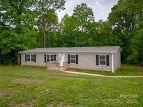 Charming single-story home with black shutters, covered front porch, and surrounded by lush greenery at 105 Peridot Dr, Statesville, NC 28625