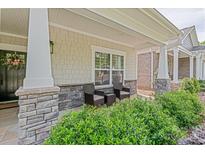 Inviting covered porch with stone pillars, cozy seating, and lush landscaping for relaxation and curb appeal at 1109 Bunch Dr, Statesville, NC 28677