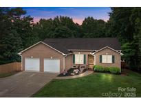 Charming brick home features a two-car garage, manicured lawn, and lush landscaping at 144 Sea Trail Dr, Mooresville, NC 28117