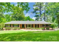 Charming brick home with lush green lawn and mature trees providing ample shade at 2001 Lakeview Dr, Pineville, NC 28134