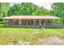 Charming single-story home with a metal roof, inviting front porch, and decorative wagon wheel accents at 3988 Old Hickory Rd, Lancaster, SC 29720