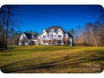 Expansive estate featuring a large lawn, balconies, and a stately facade under a bright blue sky at 450 Greywalls Ln, Iron Station, NC 28080