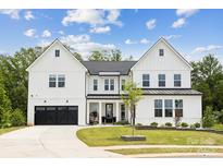 Stunning two-story white farmhouse-style home with a black garage door and beautifully landscaped front yard at 4530 Tournette Dr # 18, Indian Land, SC 29707