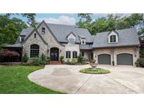 Charming stone home featuring a circular driveway and landscaped front yard with beautiful water fountain at 5523 Meadow Haven Ln, Charlotte, NC 28270