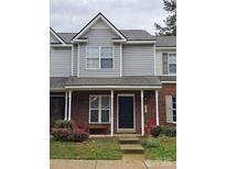 Charming townhome featuring a brick facade, covered porch, and inviting curb appeal with colorful chairs and plantings at 7562 Petrea Ln, Charlotte, NC 28227