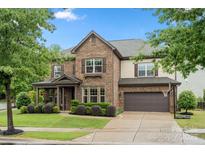 Charming two-story brick home with a well-manicured lawn and a basketball hoop above the garage at 9530 Hightower Oak St, Huntersville, NC 28078