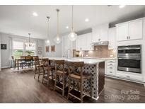 A spacious kitchen with white cabinetry, stainless steel appliances, and large center island with seating at 9530 Hightower Oak St, Huntersville, NC 28078