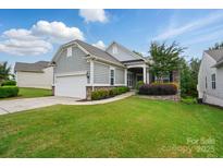 Charming home featuring a two-car garage, stone accents, manicured lawn, and lush landscaping at 1030 Pinehurst Ln, Fort Mill, SC 29707