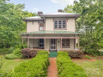 Charming two-story home with a covered porch, green metal roof, and a well-maintained front yard, blending historical charm at 1120 N College St, Mount Pleasant, NC 28124