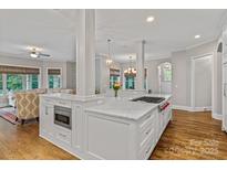 Bright kitchen with a spacious island featuring white cabinets, marble countertops, and hardwood floors at 129 Alder Springs Ln, Mooresville, NC 28117