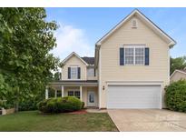 Two-story home features a light yellow exterior, attached garage, and blue shutters at 1534 Piney Church Rd, Concord, NC 28025