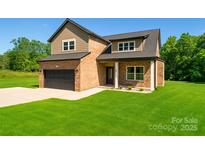 Charming two-story home with brick and siding, black garage door and a well-manicured lawn at 207 9Th Ne Ct, Conover, NC 28613