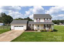 Charming two-story home featuring a well-manicured lawn, attached garage, and a welcoming front porch with rocking chairs at 2377 Mintew Cir, Lincolnton, NC 28092