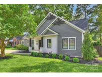 Charming home featuring a modern exterior with gray siding, a white brick porch, and meticulously landscaped front yard at 3163 Maury St, Charlotte, NC 28208