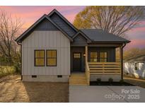 Charming single-Gathering home featuring a covered front porch, neutral siding, and dark trim against a beautiful sunset at 415 S Boyd St, Gastonia, NC 28052