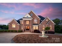 Stately two-story brick home with manicured landscaping and a circular driveway with fountain at 534 N Ingleside Farm Rd, Iron Station, NC 28080