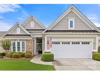 Charming home featuring brick and shingle accents, a two-car garage and manicured landscaping at 7036 Kitty Hawk Ln, Fort Mill, SC 29707