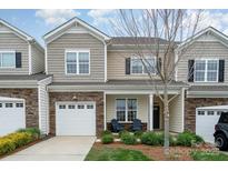 Charming townhome with stone accents, attached garage, and cozy front porch with chairs at 829 River Park Rd, Belmont, NC 28012